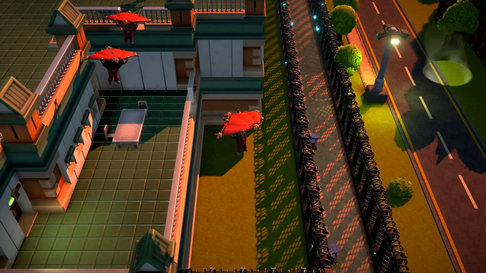 Official The Escapists 3 press screenshot showing two inmates descending on red blanket gliders past a prison building toward a razor-wire fence at dusk