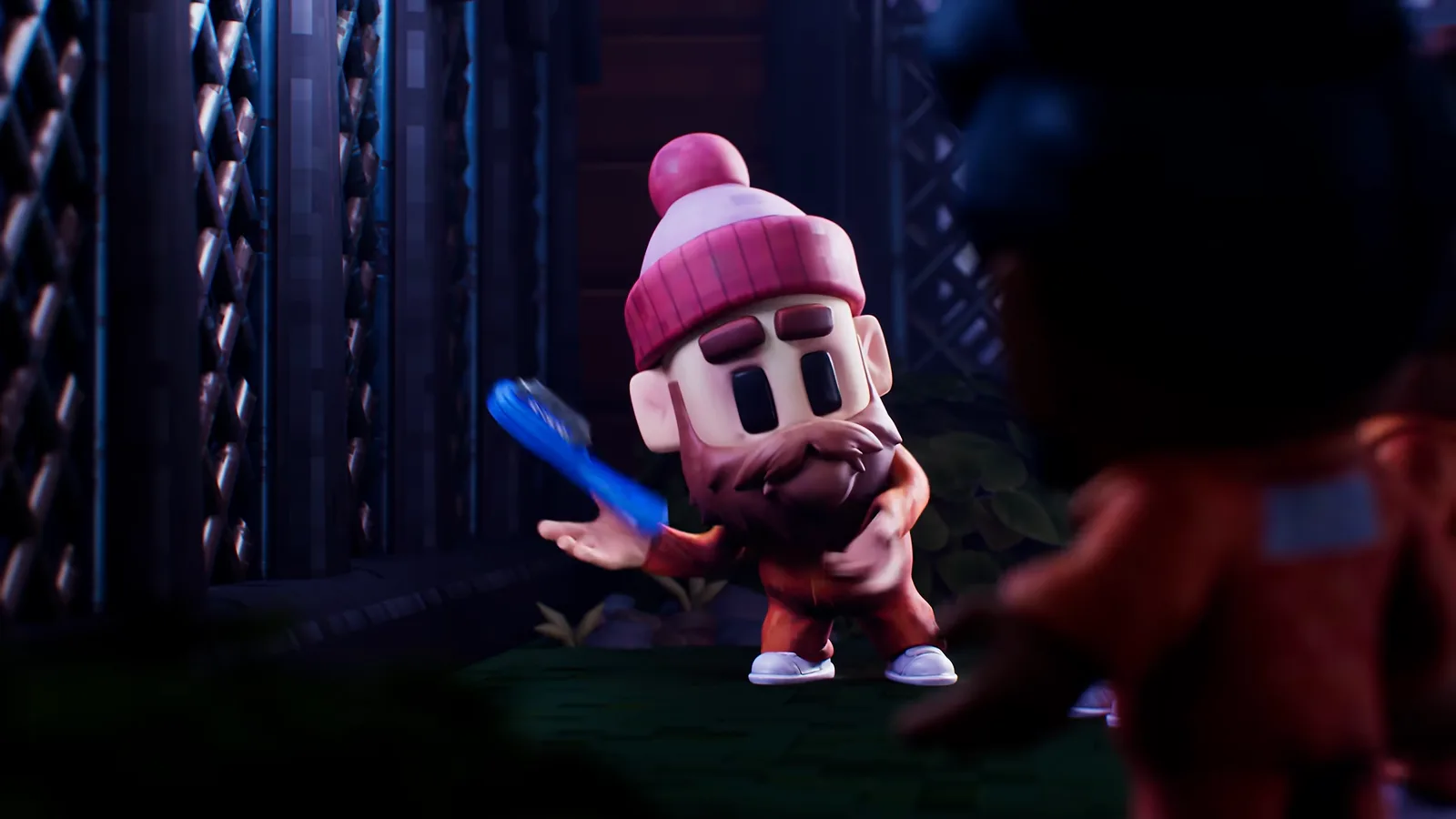 A bearded inmate in a pink bobble hat proudly displays a blue spoon, teasing the improvised tool humor of The Escapists 3.